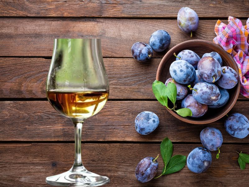 prikaz šljiva na stolu i čašice sa rakijom